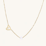 Load image into Gallery viewer, Dainty 14K gold plated stainless steel necklace with an open heart charm and a single round white bead on a cream background.