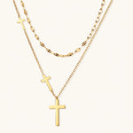 Load image into Gallery viewer, Three-layered gold necklace set with graduated cross pendants in mixed chain styles on white background.