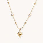 Load image into Gallery viewer, Delicate gold-plated necklace with bezel-set crystals and small heart pendant on beige background