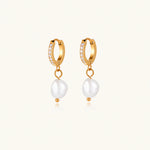 Load image into Gallery viewer, Gold huggie hoop earrings with pavé crystals and white freshwater pearl drops on cream background