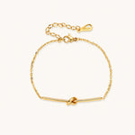 Load image into Gallery viewer, Delicate gold chain bracelet with minimalist bar and centered knot detail on cream background