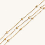 Load image into Gallery viewer, Three-strand gold-plated bracelet with clustered ball beads and adjustable clasp on cream background