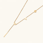 Load image into Gallery viewer, Gold Y-shaped necklace with L-O-V-E letter charms and vertical bar pendant on delicate chain against cream background