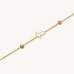 Load image into Gallery viewer, Gold chain bracelet with white mother of pearl butterfly pendant and two bezel-set crystals on cream background