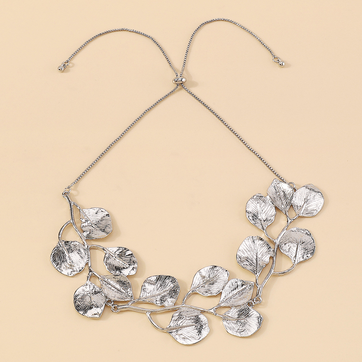 Golden Leaf Vintage Fig Leaf Necklace silver leaf necklace displayed on a beige background.