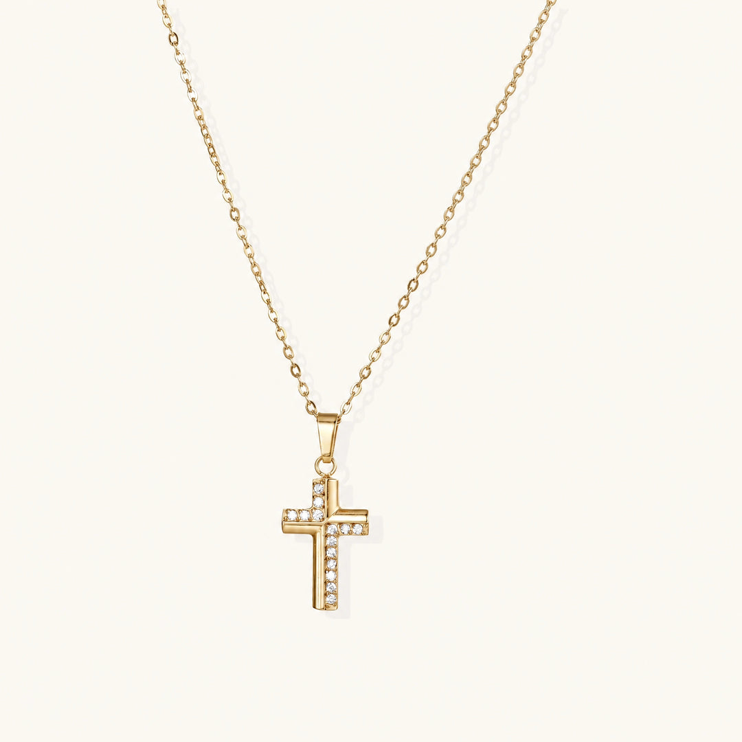 Gold-plated stainless steel cross necklace with crystal embellishments on adjustable chain against light background.