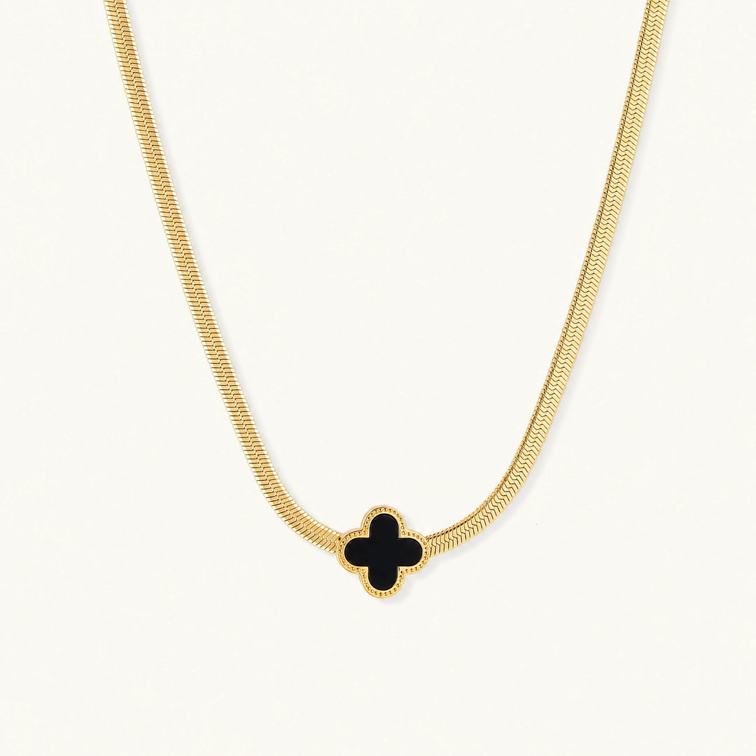 Dainty 18K gold-plated herringbone chain necklace with black enamel quatrefoil clover pendant on white background