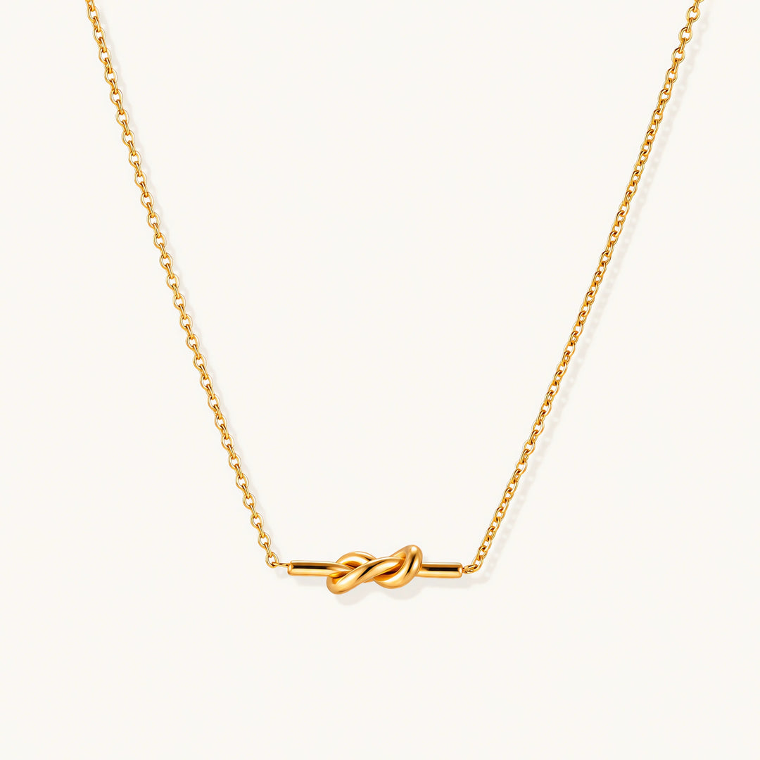 Dainty 18K gold plated necklace with infinity knot pendant on delicate chain against white background