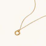 Load image into Gallery viewer, Delicate gold-plated necklace with three interlocking circle rings forming a minimalist knot pendant on cream background
