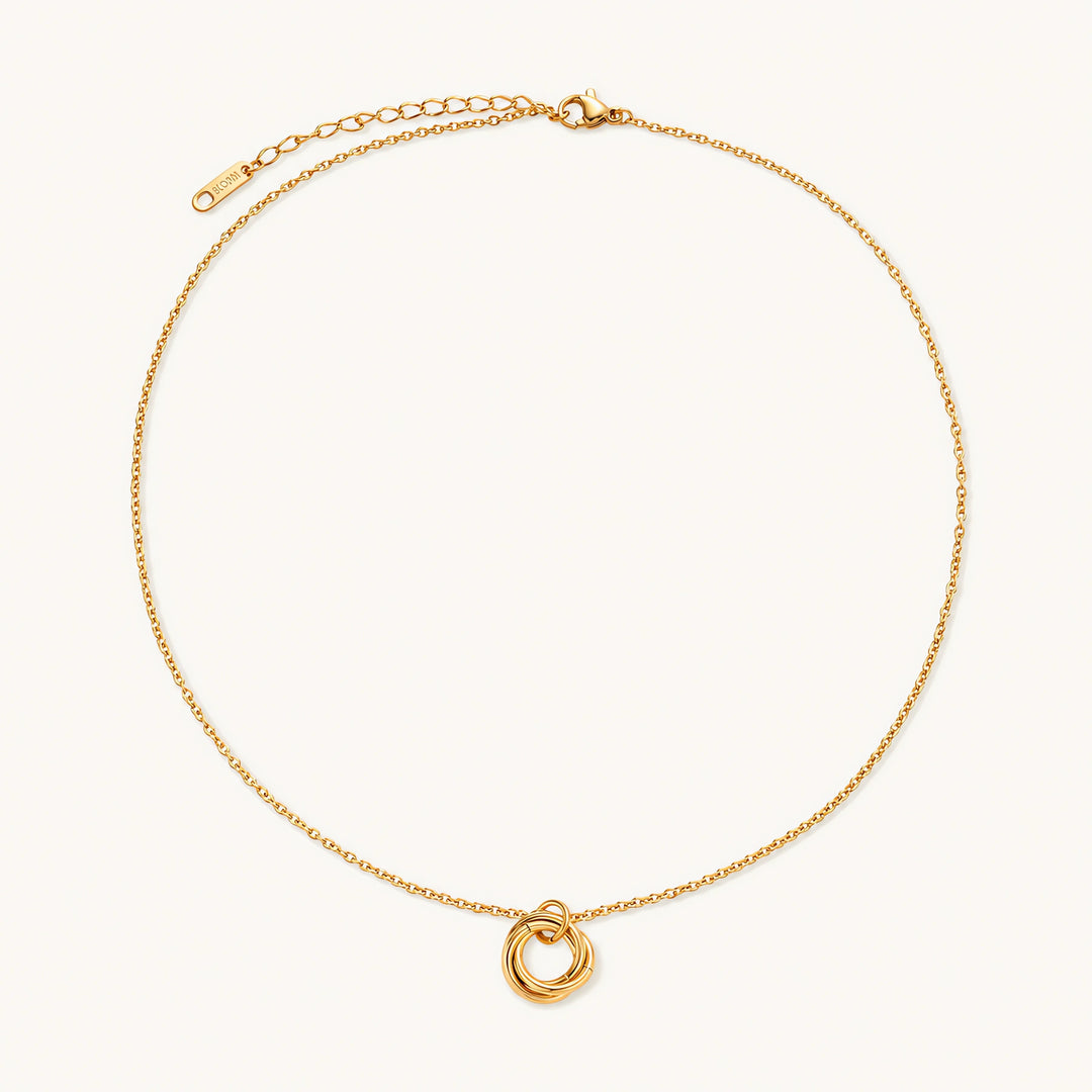Delicate gold-plated necklace with three interlocking circle rings forming a minimalist knot pendant on cream background