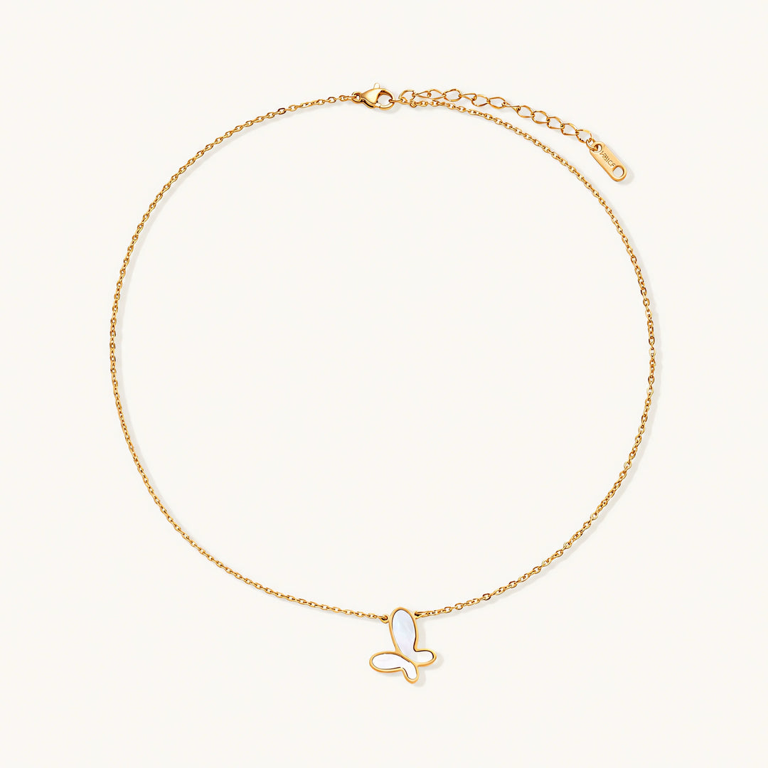 Gold-plated butterfly pendant with iridescent mother of pearl inlay on delicate chain against cream background.