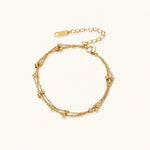 Load image into Gallery viewer, Three-strand gold-plated bracelet with clustered ball beads and adjustable clasp on cream background
