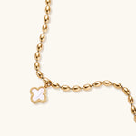 Load image into Gallery viewer, 18K gold-plated oval bead bracelet with a four-leaf clover charm in mother-of-pearl or black enamel, adjustable lobster clasp, on white background.
