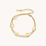 Load image into Gallery viewer, Double-layer gold-plated bracelet with quatrefoil and star charms on cream background, 18K gold finish.
