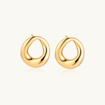 Load image into Gallery viewer, Pair of polished 18K gold-plated stainless steel teardrop earrings with hollow centers on cream background
