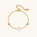 Load image into Gallery viewer, Gold chain bracelet with white mother of pearl butterfly pendant and two bezel-set crystals on cream background
