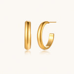 Load image into Gallery viewer, Chunky tubular hoop earrings in warm 14K gold-plated finish with smooth polished surface on cream background.
