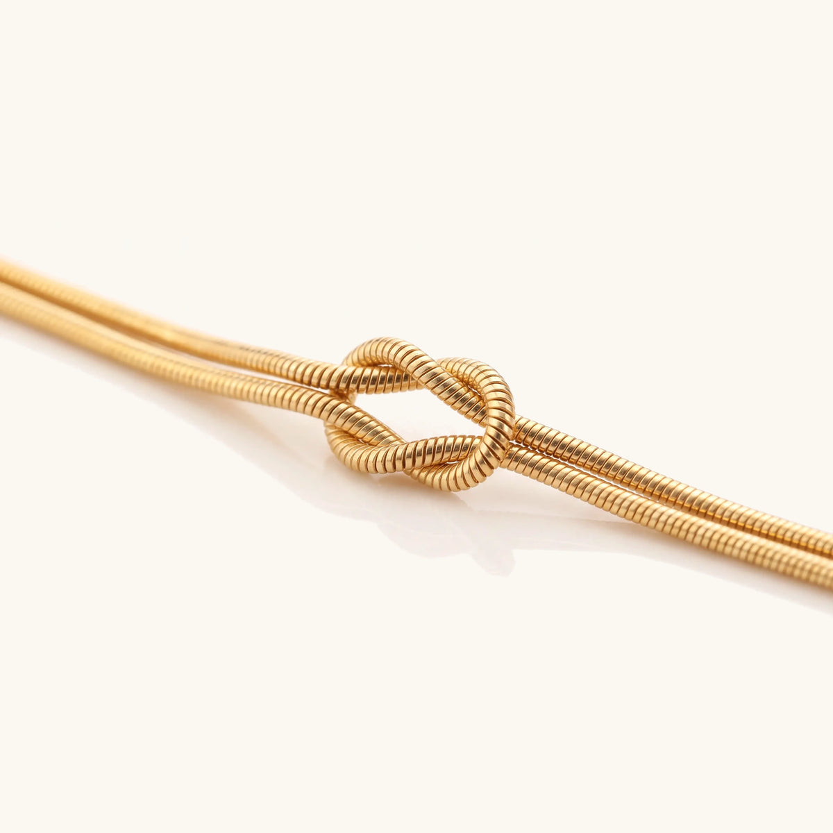Close-up of the reef knot on a fine gold snake chain bracelet