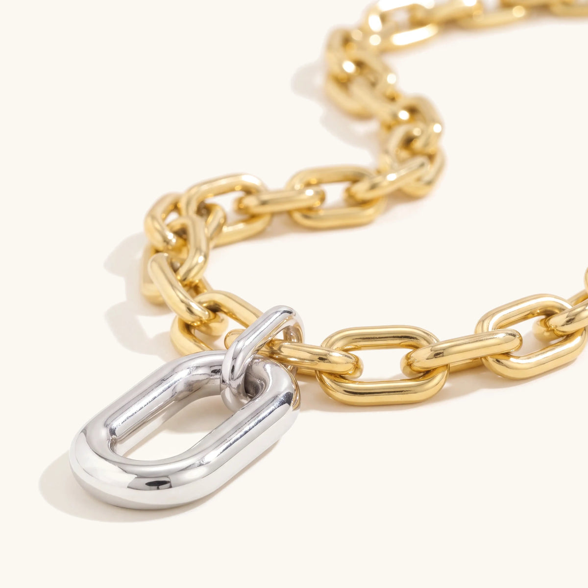Close-up of the silver oval drop on the chunky gold paperclip chain