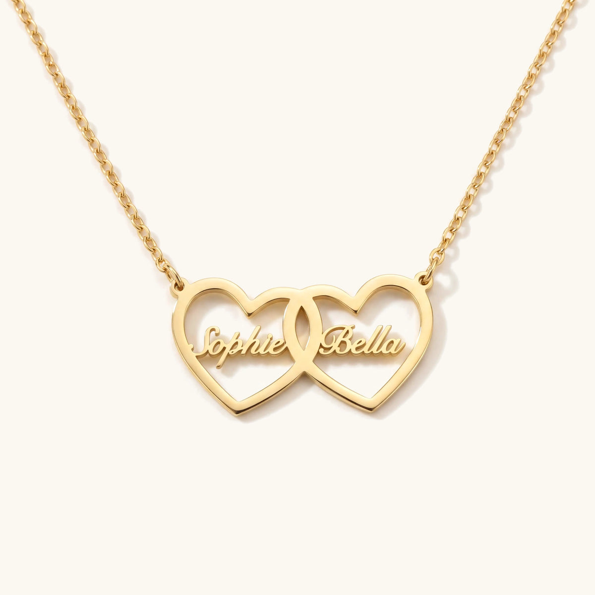 Dainty Personalized Dual Heart Name Necklace – two interlocking gold hearts with script names