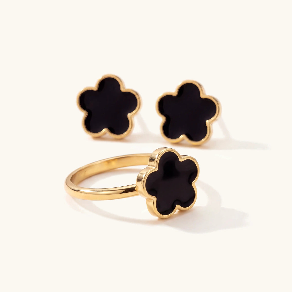 Close-up of the black flower ring and stud earrings from the gold clover set
