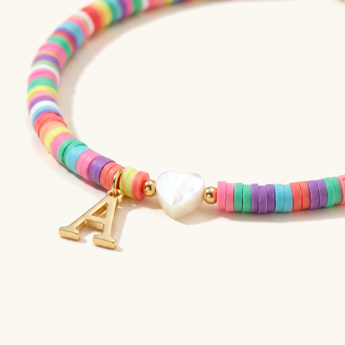 Close-up of the heart initial charm and colorful beads on the anklet