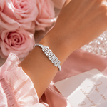 Load image into Gallery viewer, Personalized Family Name Herringbone Chain Bracelet sparkling silver-toned bracelet with rectangular pavé stones worn on wrist with pink roses and satin background.
