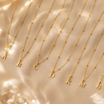 Load image into Gallery viewer, Dainty Satellite Chain Letter Initial Necklace delicate gold initial necklaces with A, B, C, D, K, M letter charms arranged on beige satin fabric.
