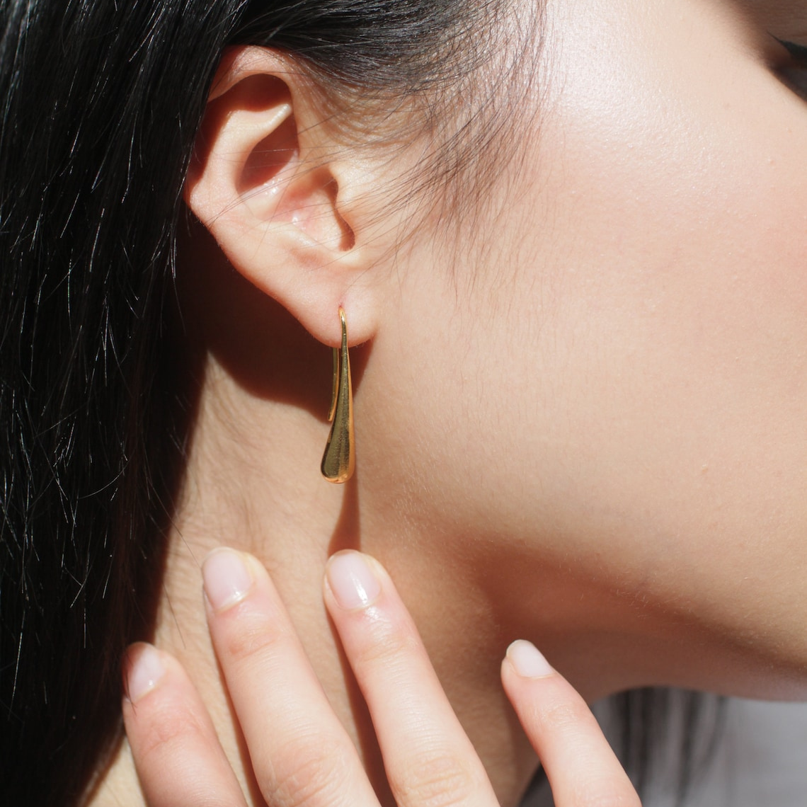 Water drop french hook earrings person wearing a gold water drop earring against a blurred background