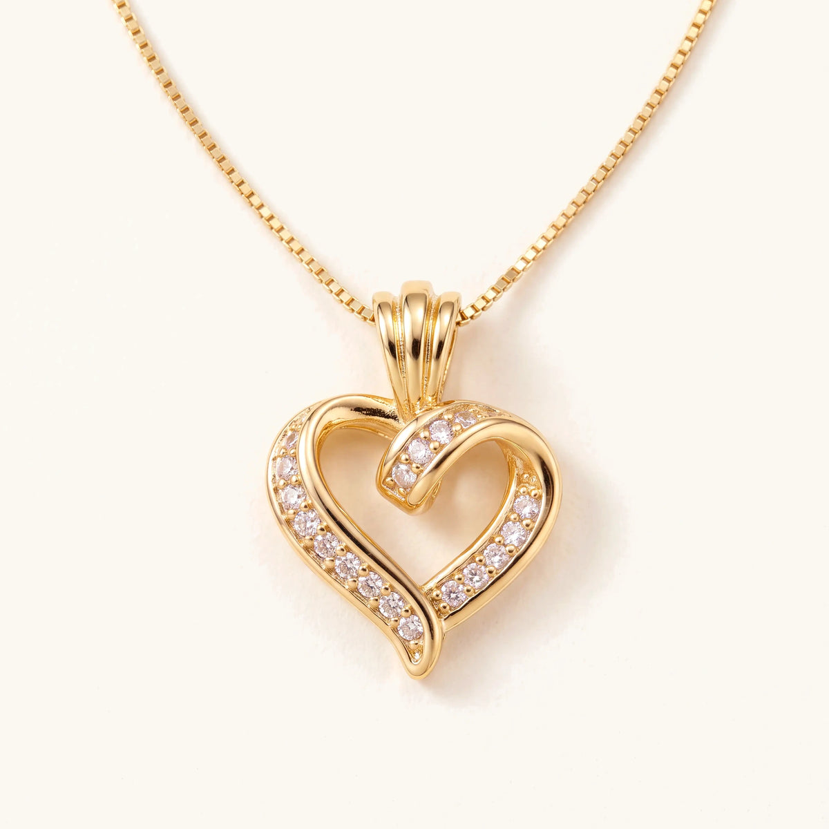 Gold heart pendant necklace with sparkling stones on a cream background