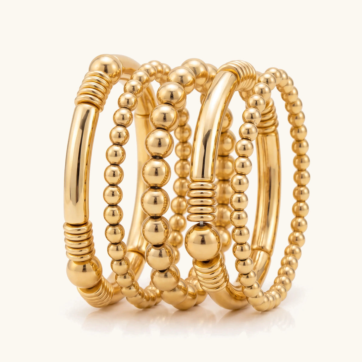 Set of five gold stretch bead bracelets stacked together on a cream background