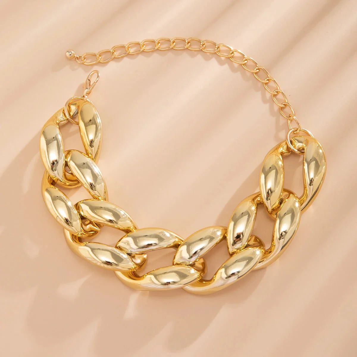 Exaggerated Chunky Cuban Link Choker Necklace gold chunky Cuban link chain displayed on a beige background.