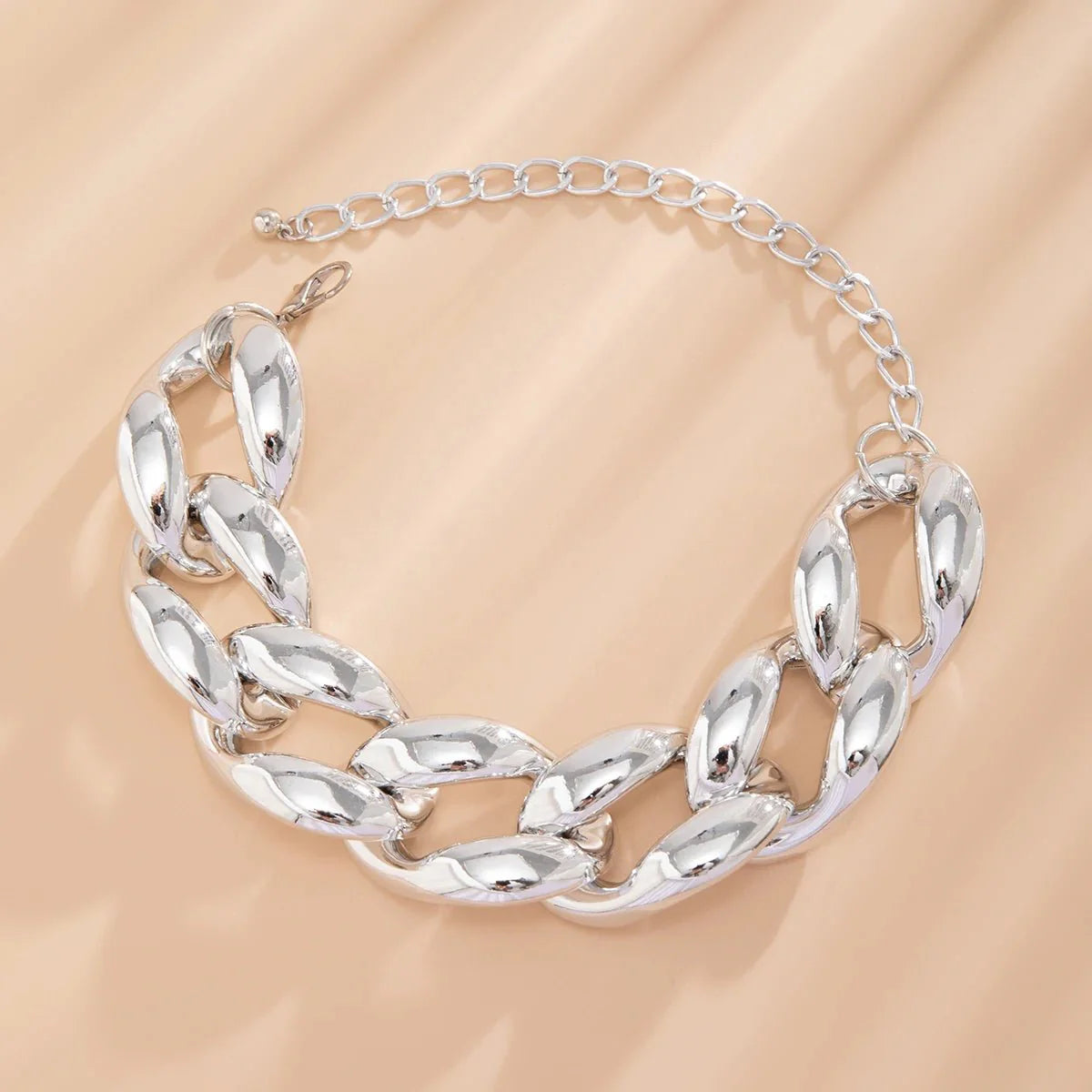 Exaggerated Chunky Cuban Link Choker Necklace silver chunky Cuban link chain displayed on a beige fabric background.