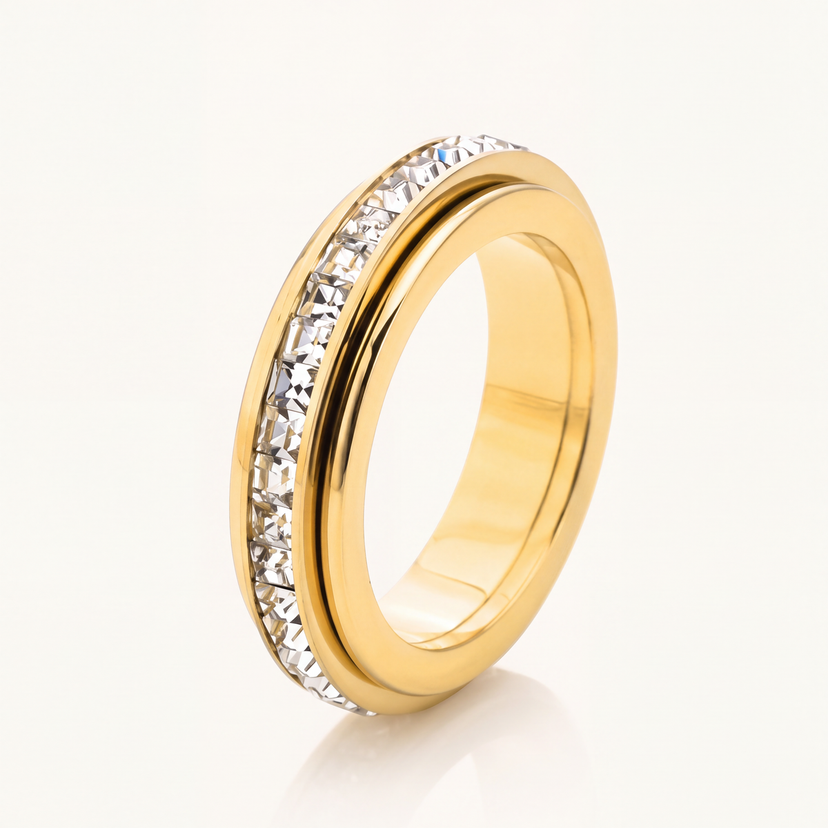 Gold band ring set with a row of sparkling stones on a cream background