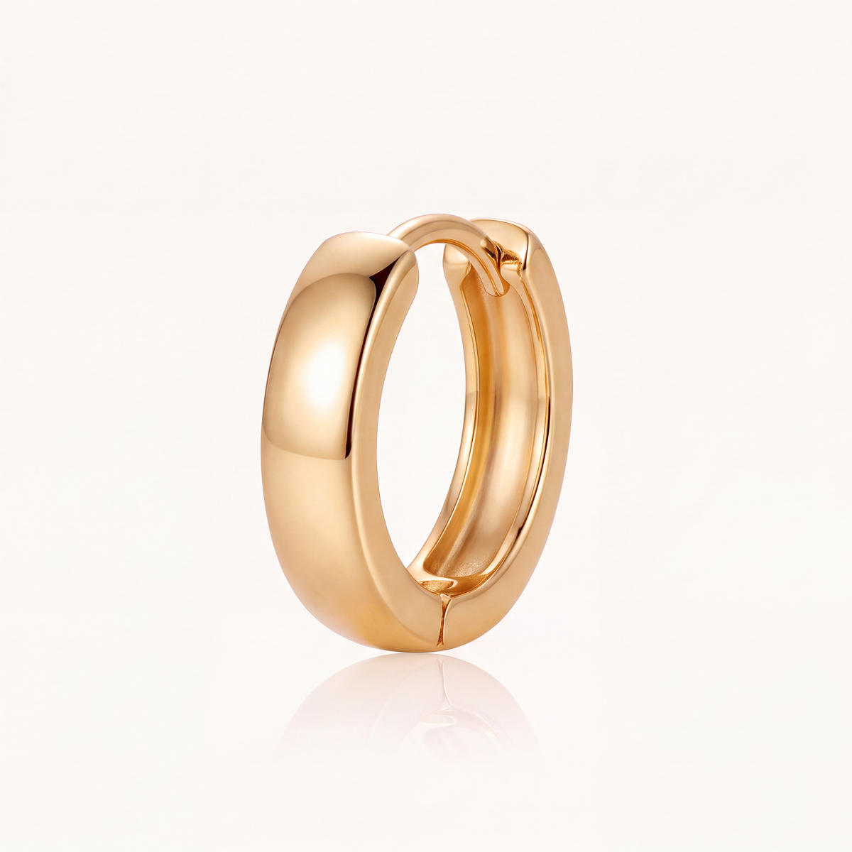 Side view of a minimalist gold huggie hoop earring showing band thickness and hinge
